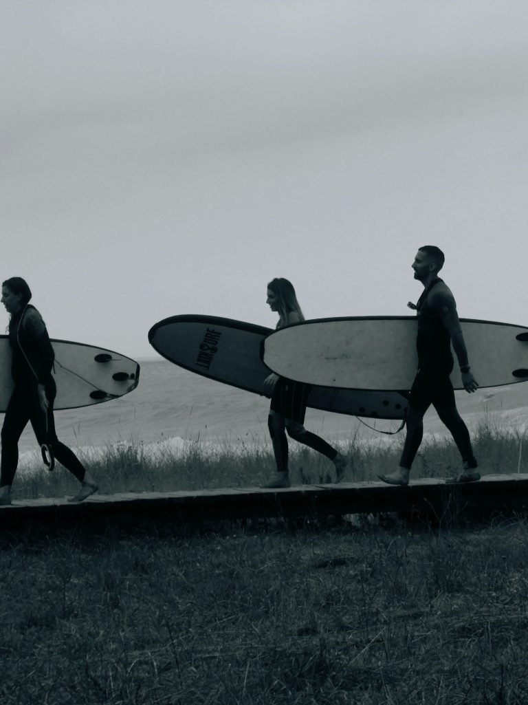 Group of people walking together with surfboards, representing team collaboration